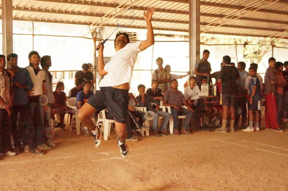 A badminton player jumps to strike the shuttle during a match.