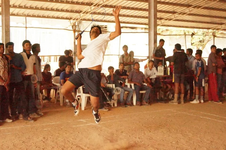 A badminton player jumps to strike the shuttle during a match.