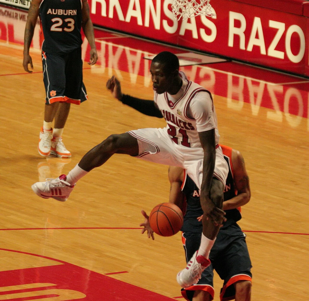 Basketball players contest a game near the basket.
