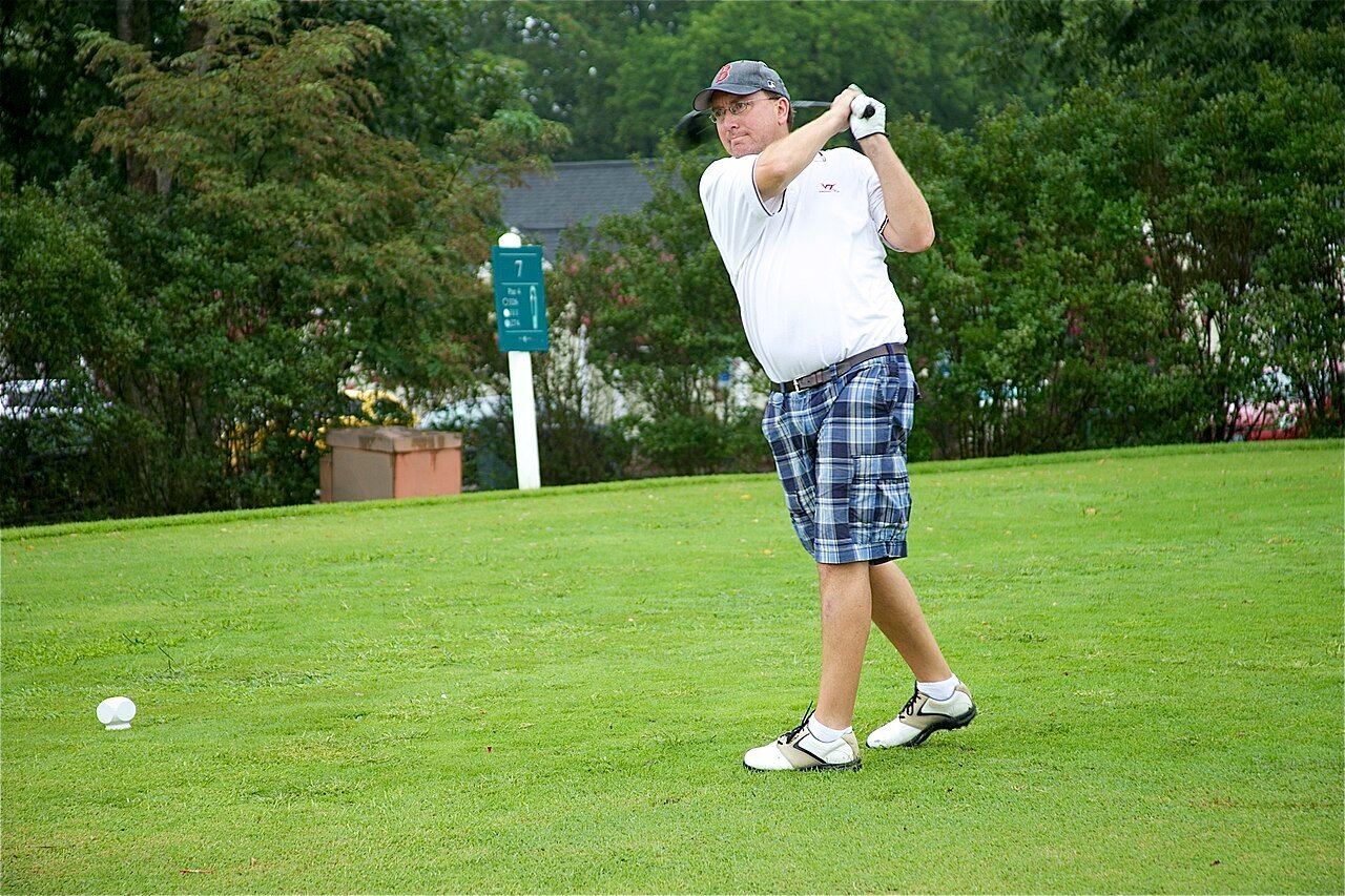 A golfer tees off during an outdoor tournament.