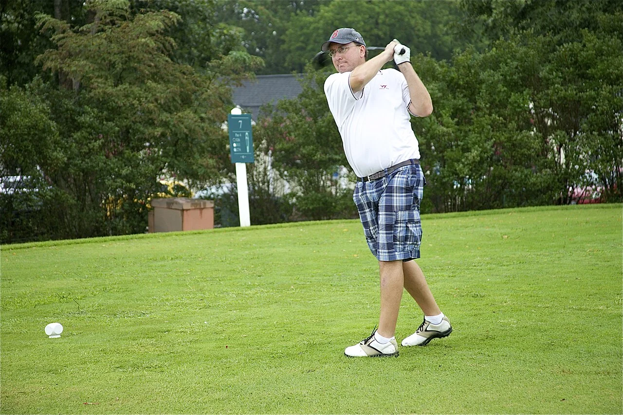 A golfer tees off during an outdoor tournament.