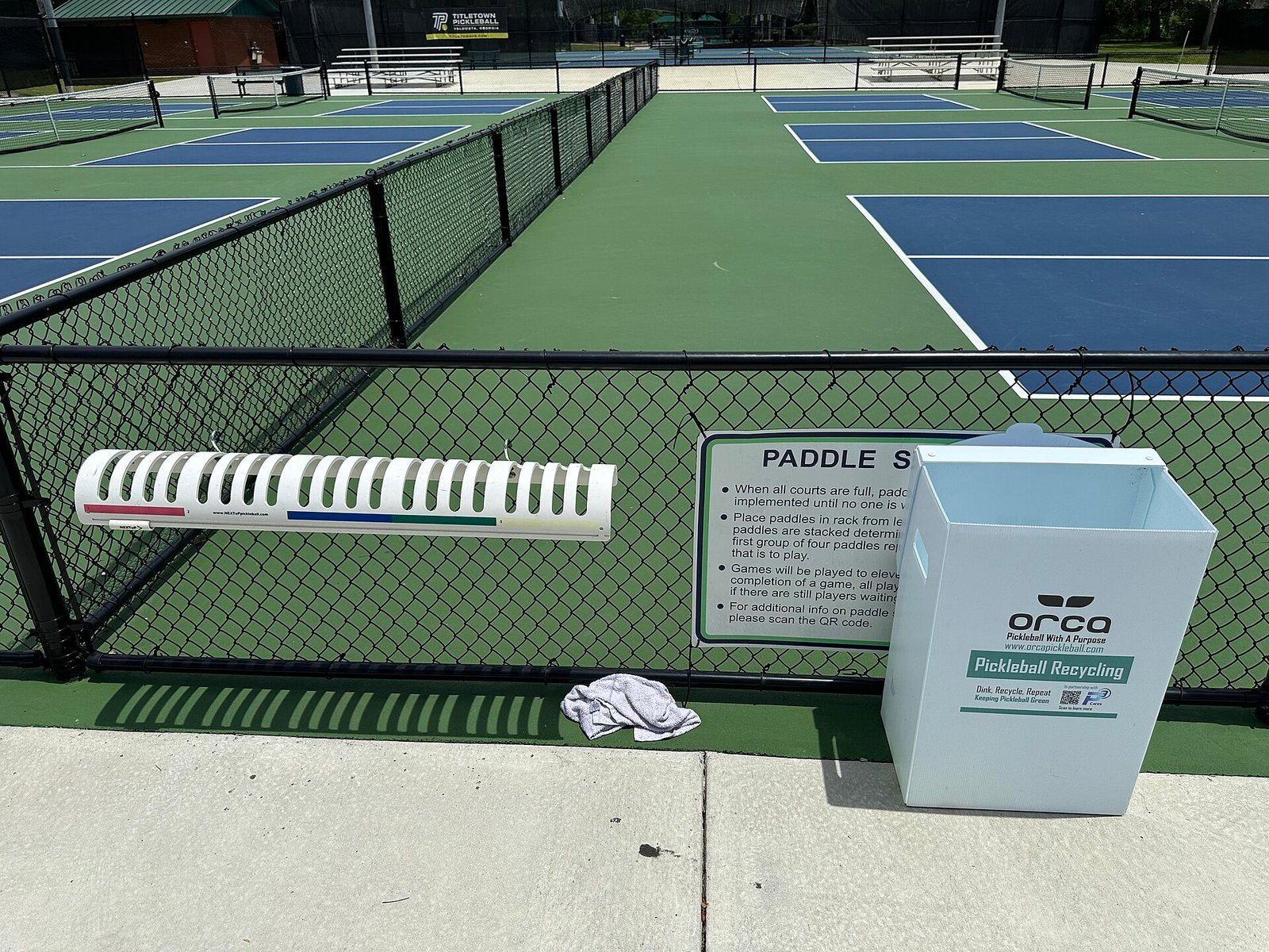 Pickleball paddles stacked beside a court before play.