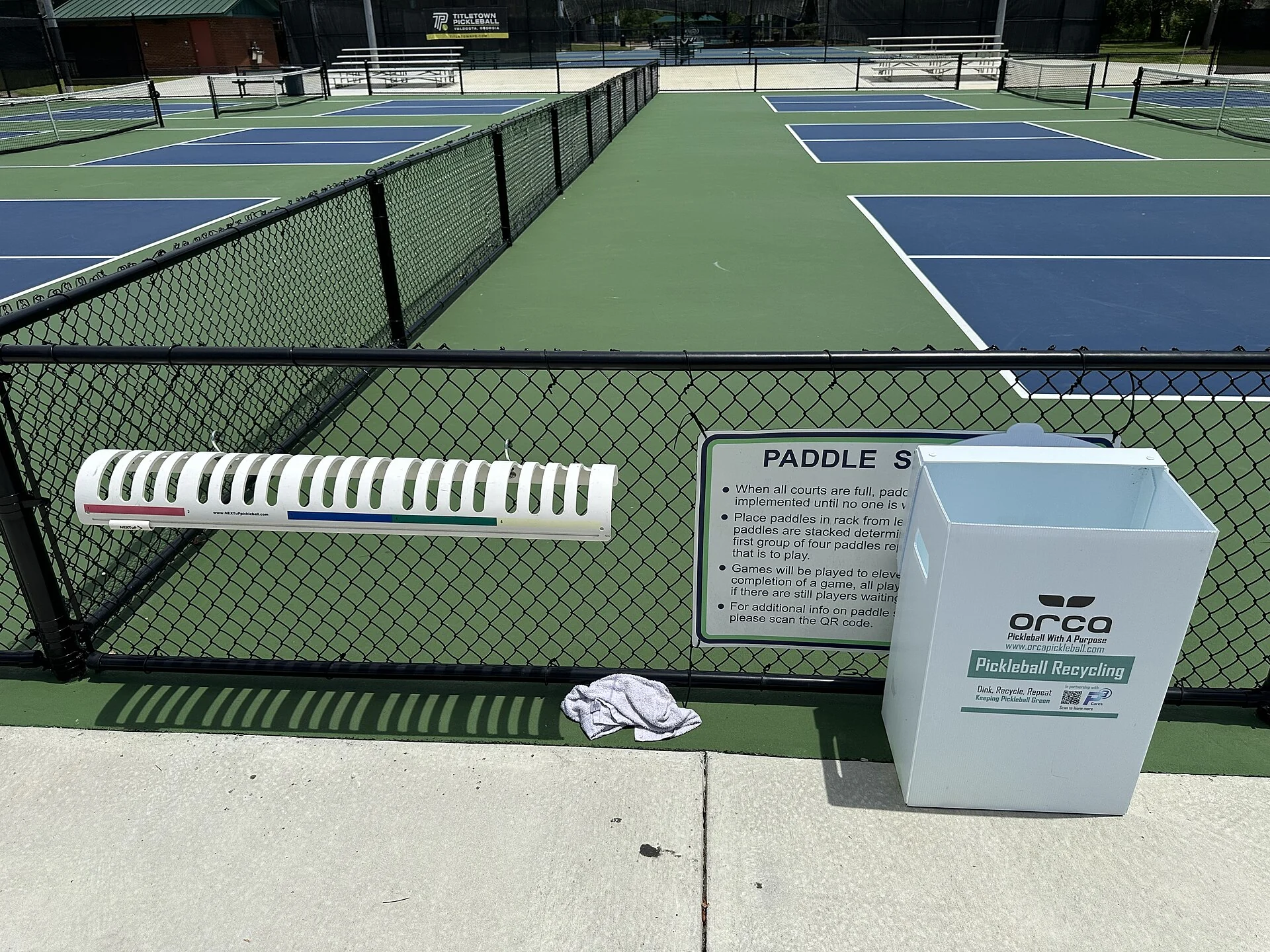 Pickleball paddles stacked beside a court before play.