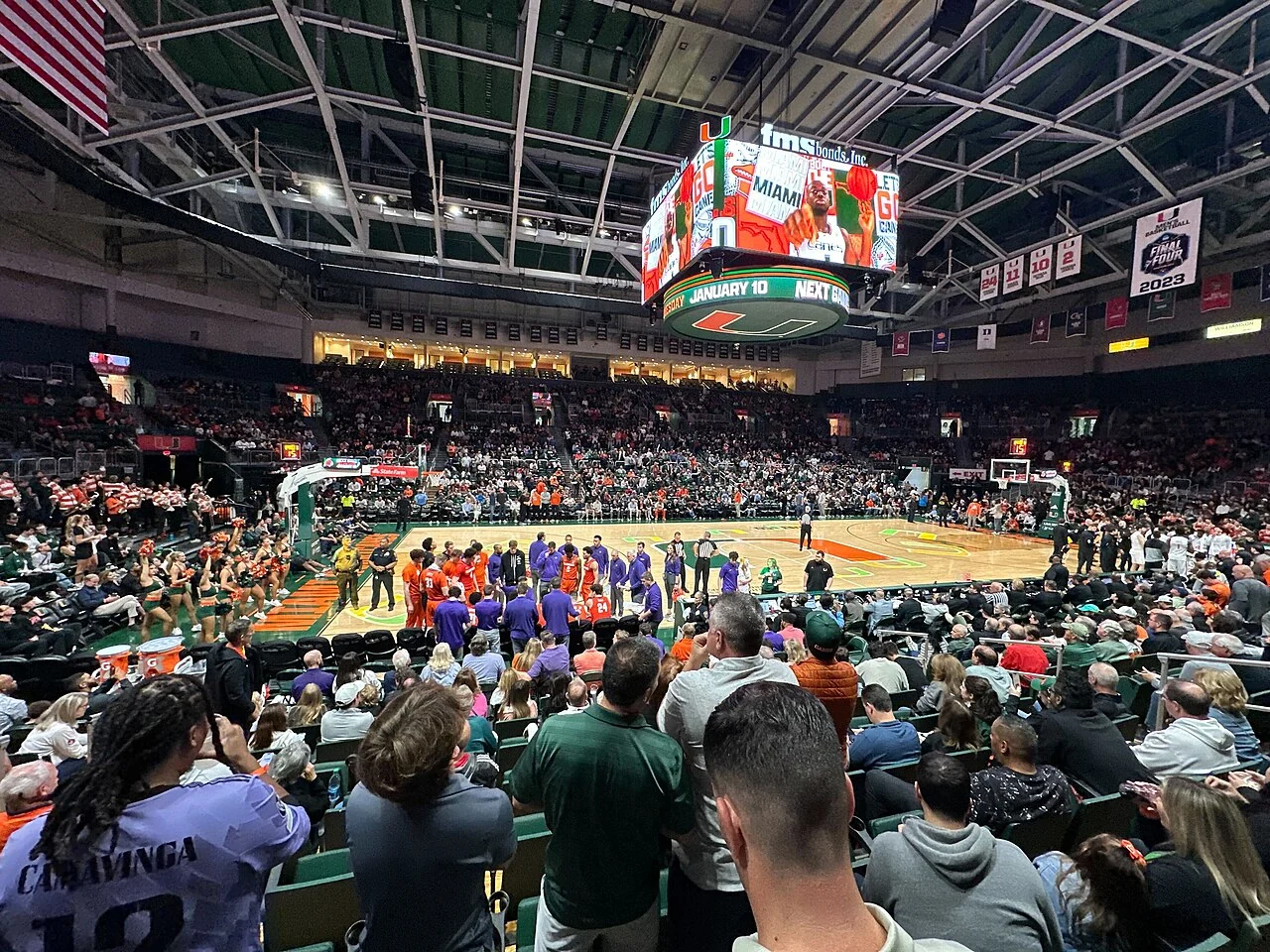 Basketball players compete in an indoor arena during a college game.