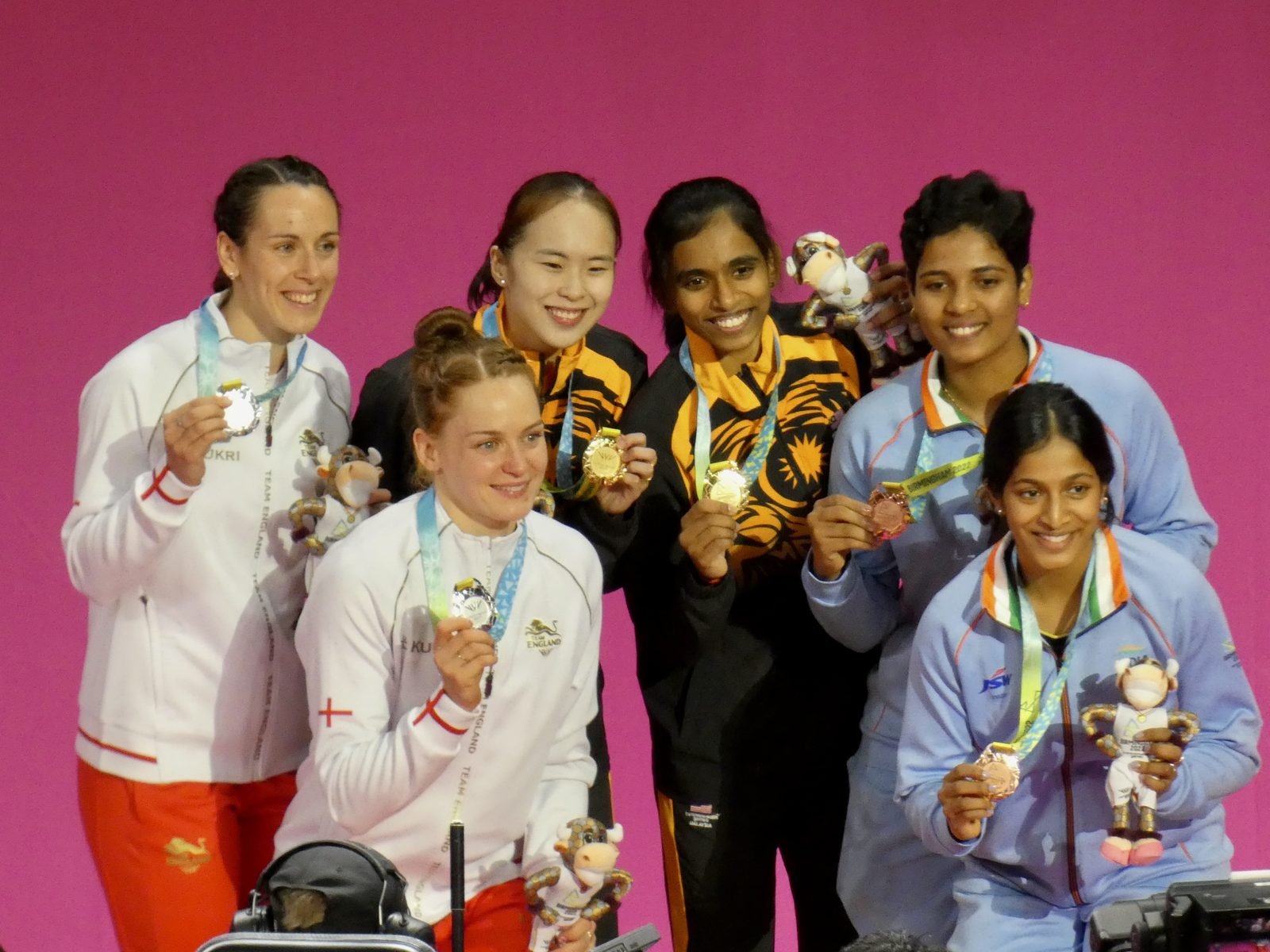 Three women's doubles badminton pairs stand on an international podium.
