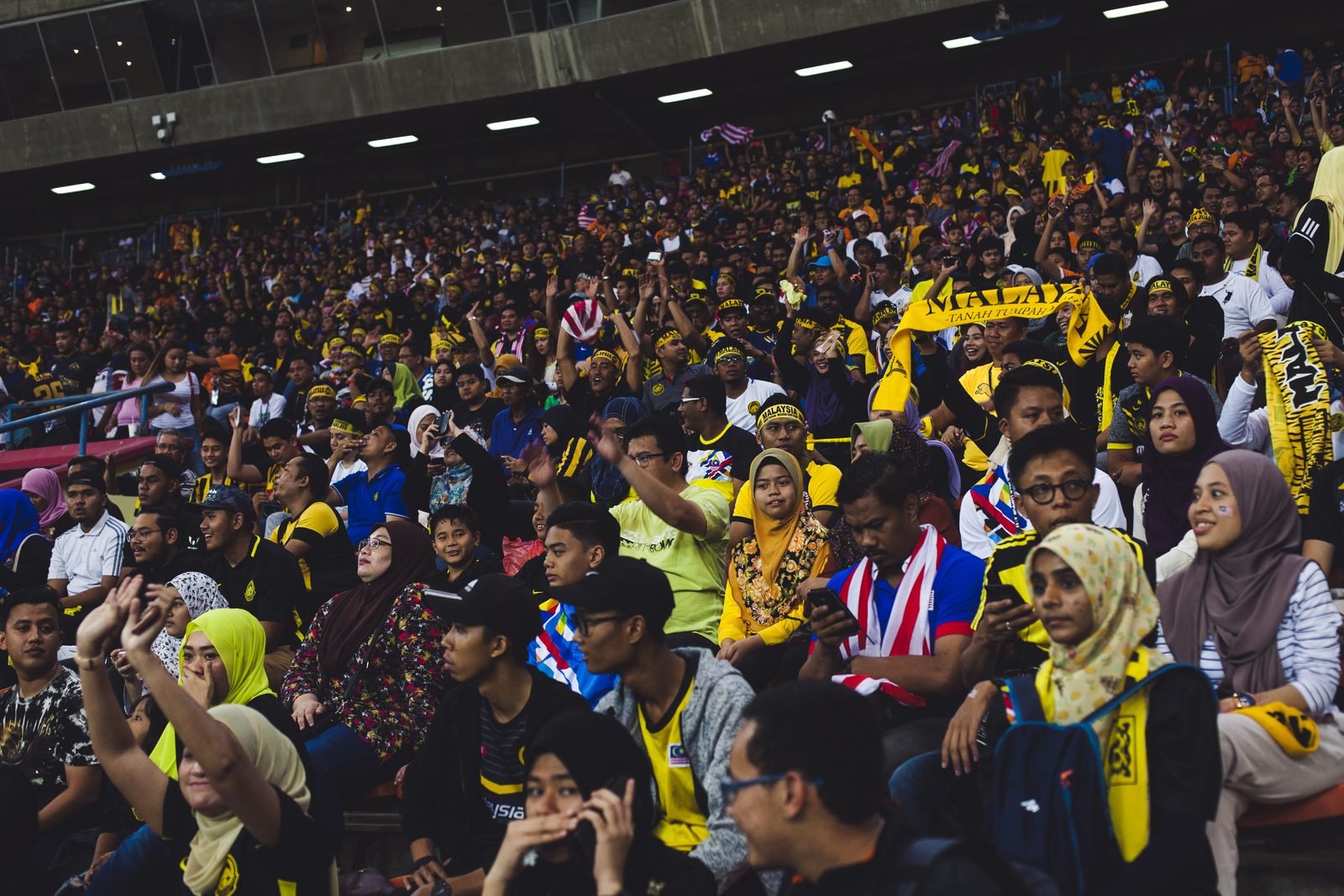 Malaysia football supporters fill a stadium stand.