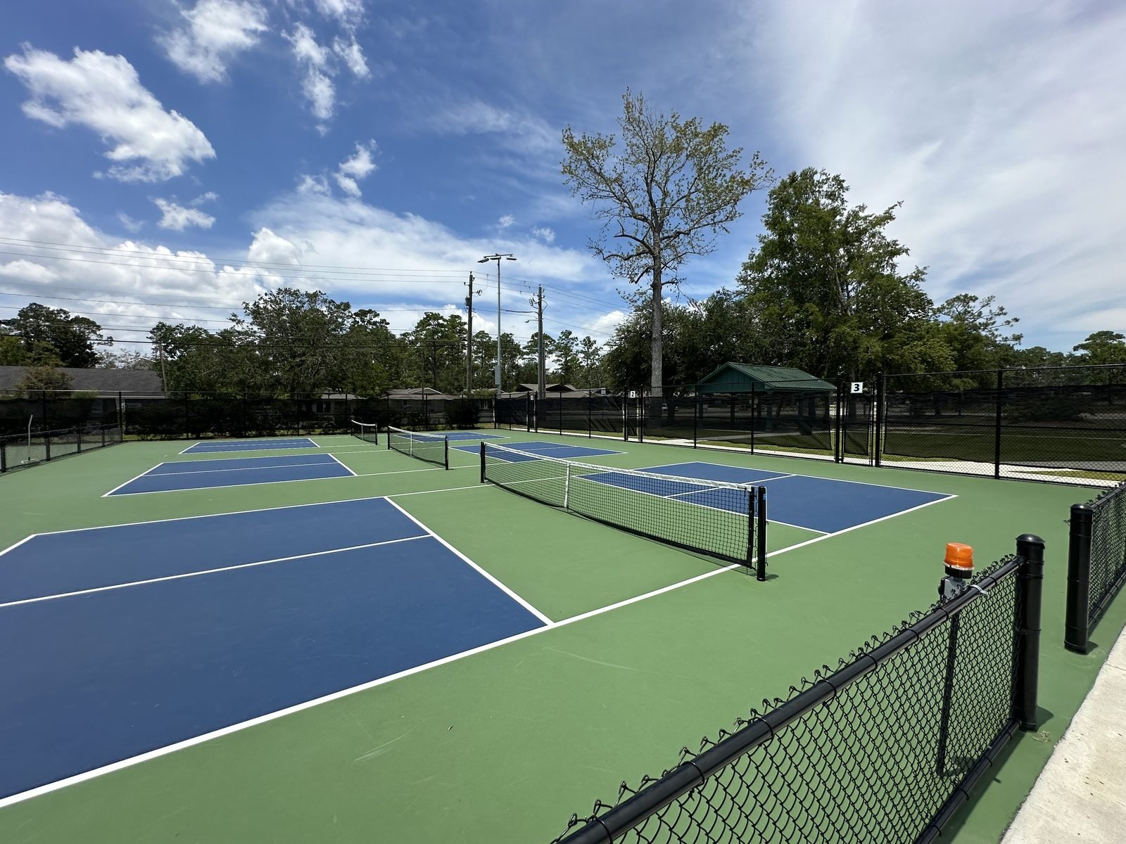 Three outdoor pickleball courts prepared for play.