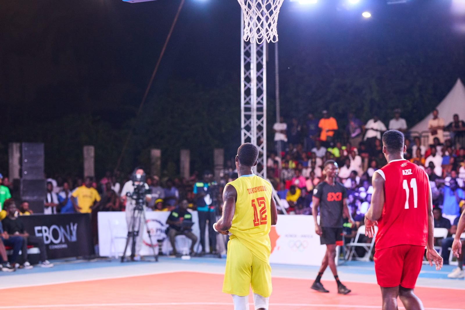 Players compete around the arc in an outdoor 3x3 basketball game.