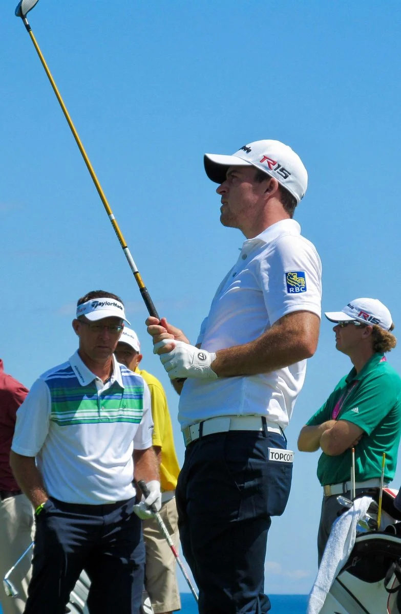 A professional golfer follows the flight of an approach shot.