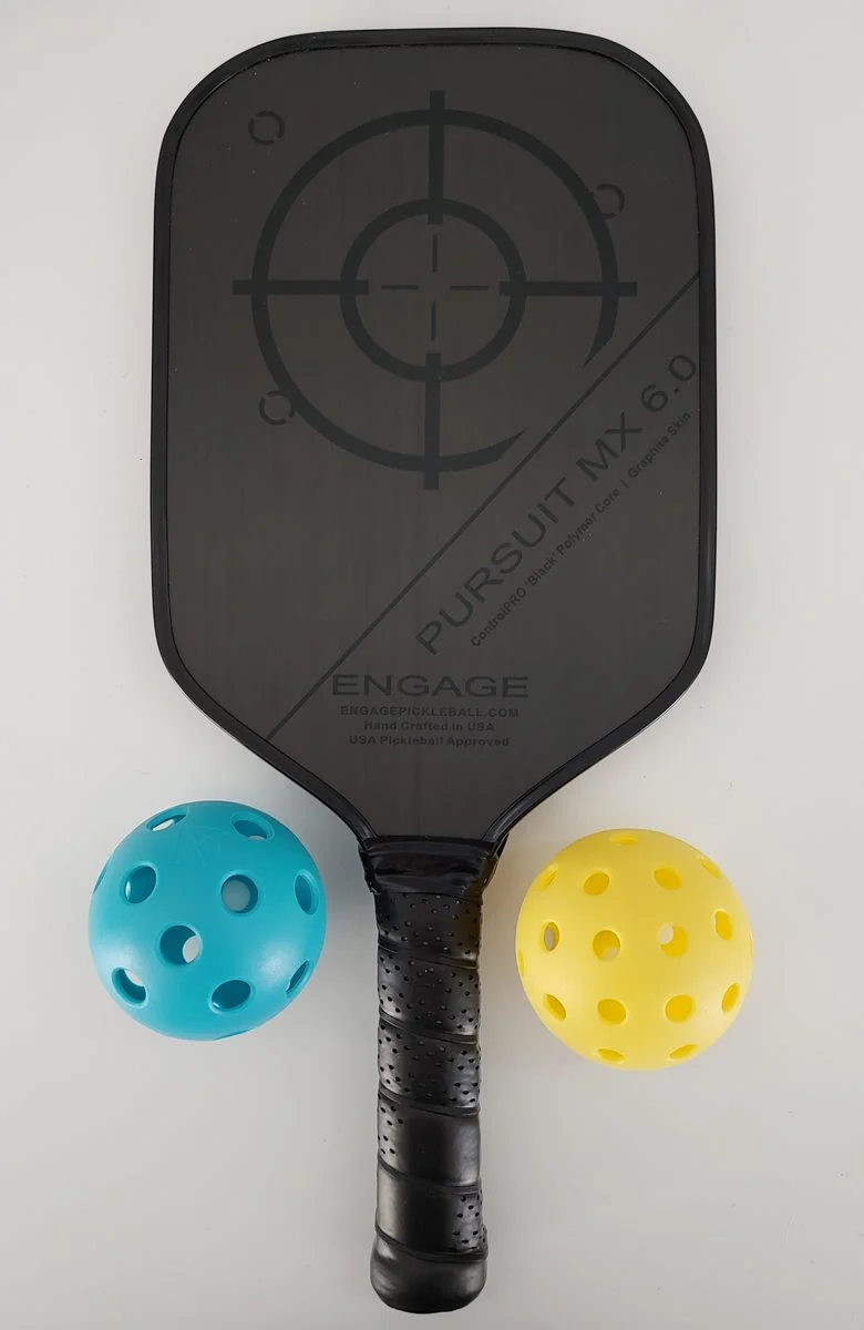A pickleball paddle rests beside two pickleballs.