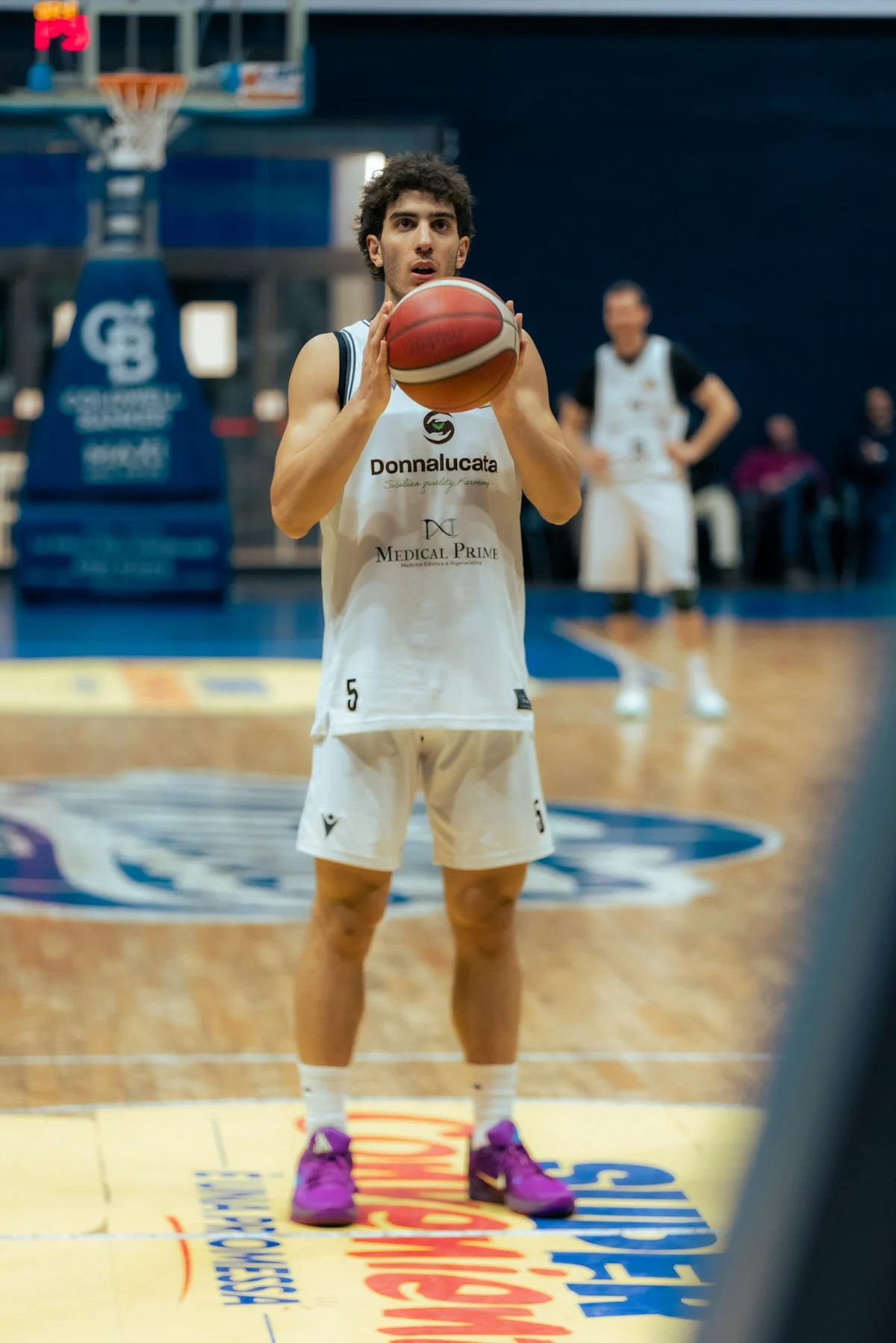 A basketball player holding a ball on court.