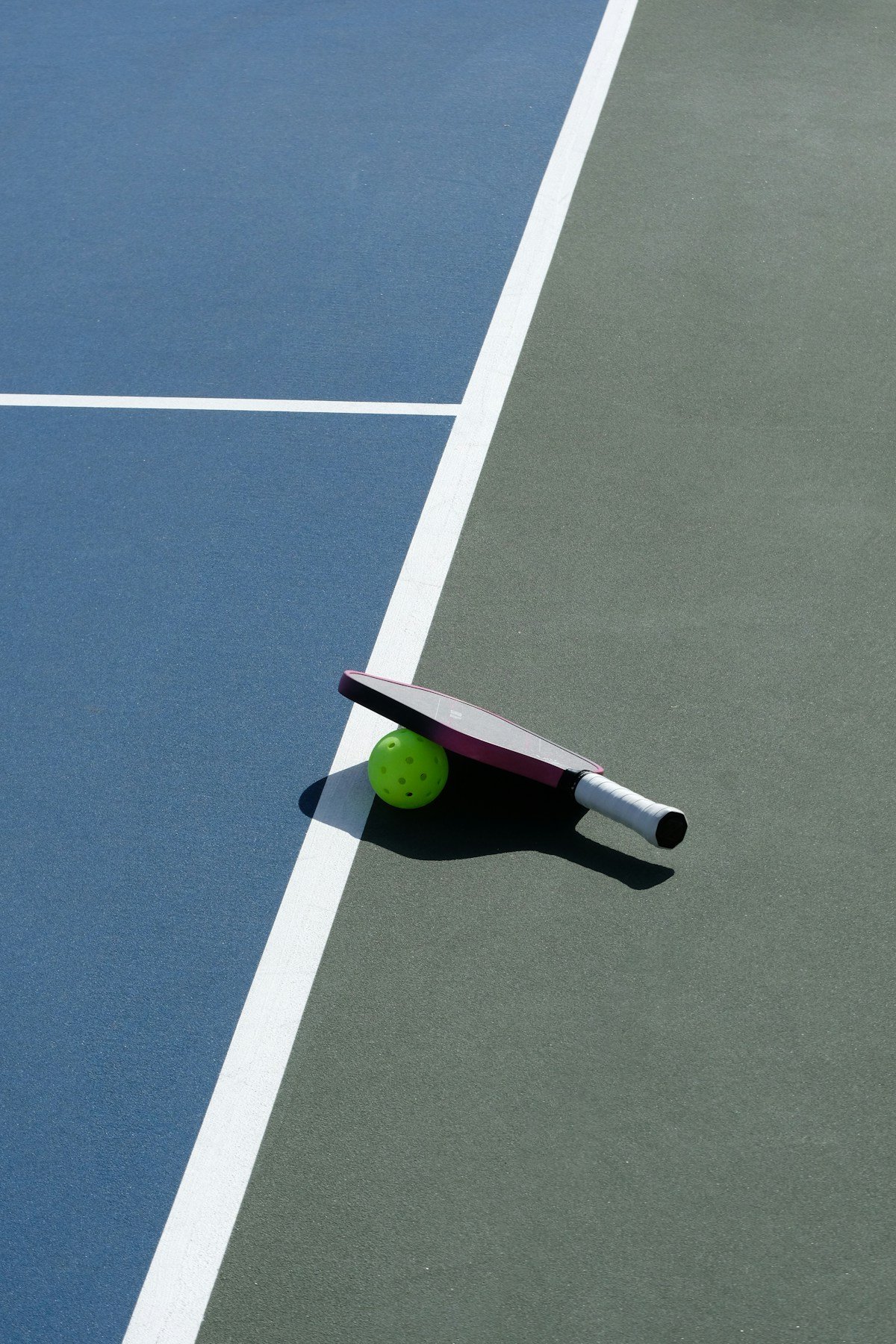 Pickleball paddle and ball on a court.