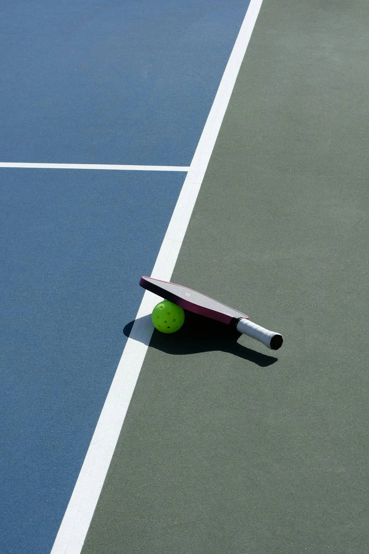 Pickleball paddle and ball on a court.