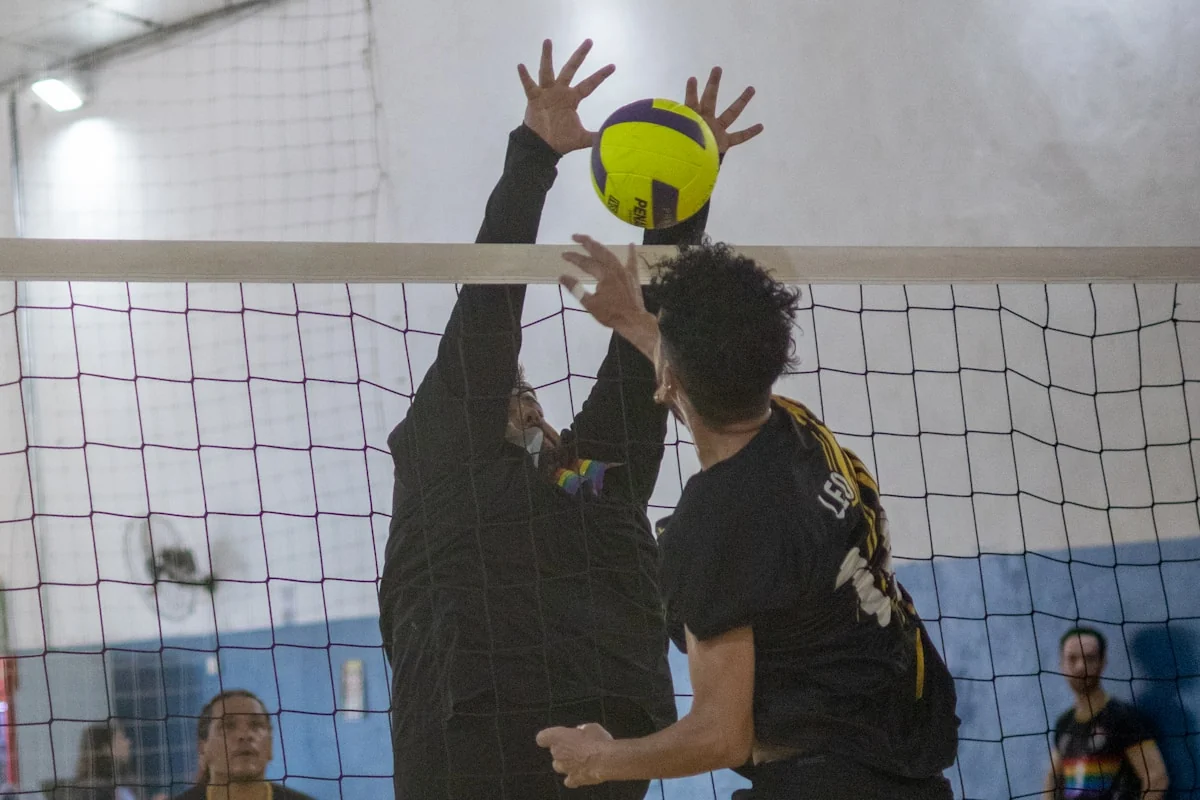 Volleyball players competing at the net.